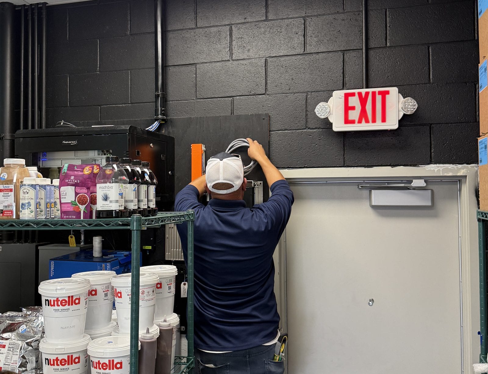Conduit being run above the back door of a store during fit-out, block wall still bare